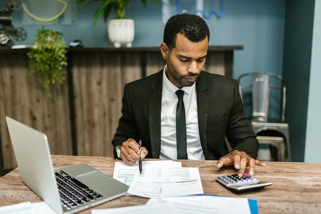 accountant looking at balance sheets and using a calculator